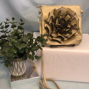 Crossbody taupe purse with rosette flower detail on the front.